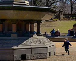 Child running around a fountain with a shadow cast to the left by a side light source