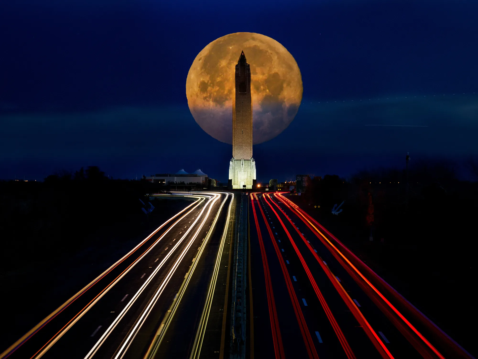 A monument with the moon above it, its walls and lines leading attention toward the subject