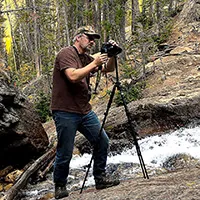 Jay Brass photographing beside Browns Falls, his camera mounted on a tripod near the rushing water.